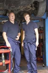 Mechanic and apprentice working on car